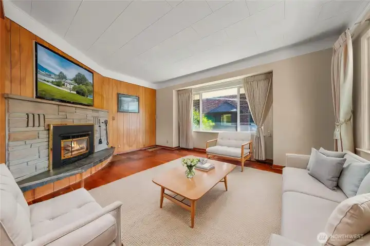 Virtually staged. Living room with gas fireplace and original wood floors Virtually staged. Living room with gas fireplace and original wood floors