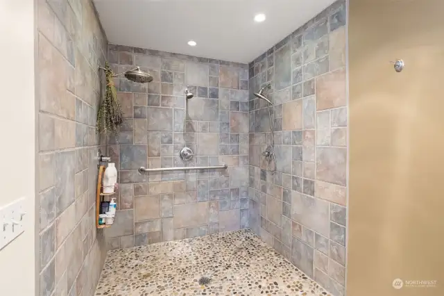 Primary custom tiled shower with triple showerheads and open-entry