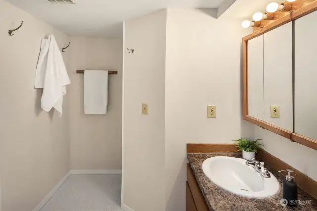 Large bathroom with tiled floors and a tile surround shower.