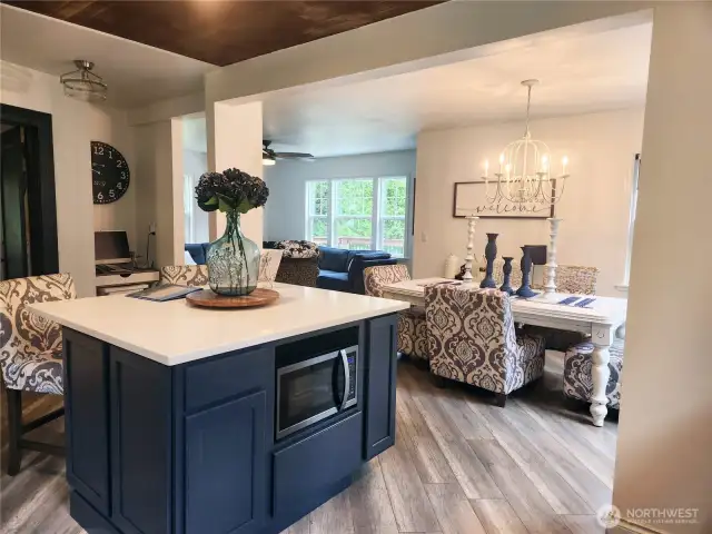 Microwave tucked away in the island to allow more countertop space in the kitchen.  View of dining and living room beyond.