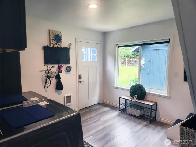 Back door entrance of home leads into the mudroom/utility space.  To the right is the stairway for second floor.  Well pumphouse in view.