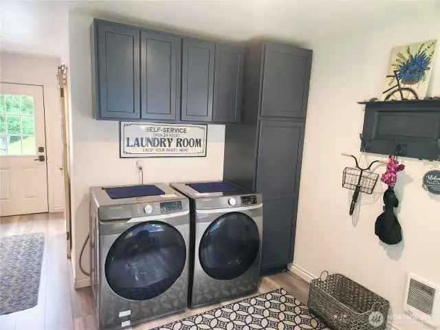 Washer and dryer to remain with home. Lots of cabinets for storage.  Hallway to the left leads to bathroom and other exit to decking. Water heater to the right of cabinets.