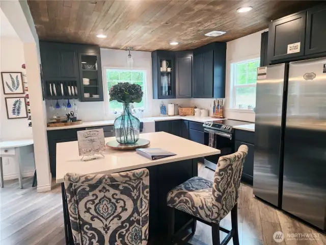 Spacious kitchen with an eat-in island, gorgeous farm sink,  and tons of cabinetry for all your cooking and storage needs.  All dishware and utensils to convey with the home.