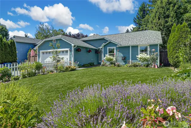 Picture perfect, beautifully landscaped yard complete with white picket fence.