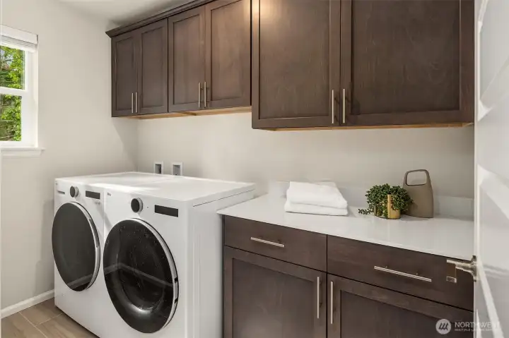 Large laundry room with folding table and storage conveniently located on upper level.