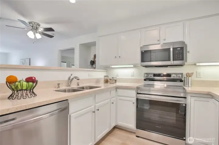 Updated kitchen with new appliances, solid surface countertops, luxury vinyl plank flooring white cabinets.
