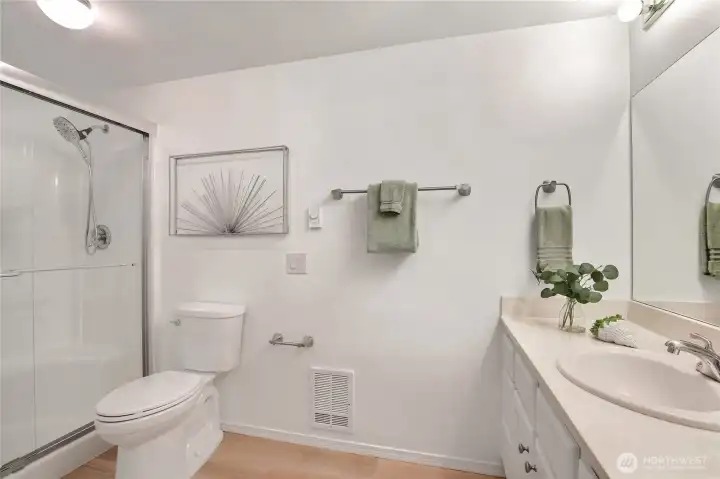 Primary bath with upgraded shower stall, glass doors, and luxury vinyl plank floors.