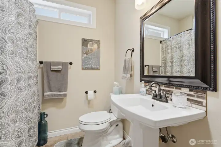 Well-maintained guest bath featuring attractive finishes and additional storage cabinetry.