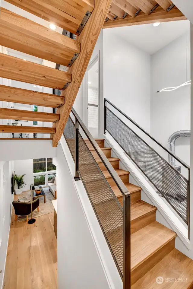 Real hardwood floors throughout the main floor lead to a floating solid-wood staircase with custom metal railings. The landing areas have wall space that accommodates art beautifully.