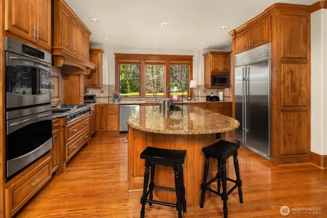 A big Chef's kitchen complete with island breakfast bar, dual wall ovens, Sub Zero Refrigerator, Viking cooktop with custom hood vent, granite counters, and beautiful rich cabinetry throughout.