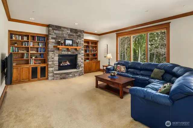 This large family room features built in shelves and cabinets, and a cozy NW Style Stone Fireplace! There is a wall mounted TV to the left side that will comes with the house if the buyer desires it.
