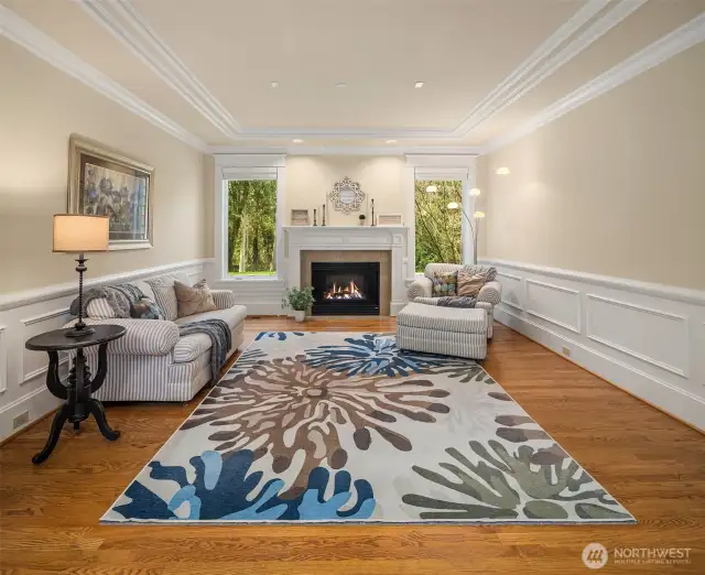 The formal living room with wainscoting, crown molding, real hardwood floors, and a gas fireplace!