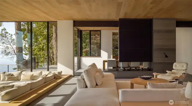 The great room flows from the upper level with two-sided fireplace down to the front room open to the Sea.