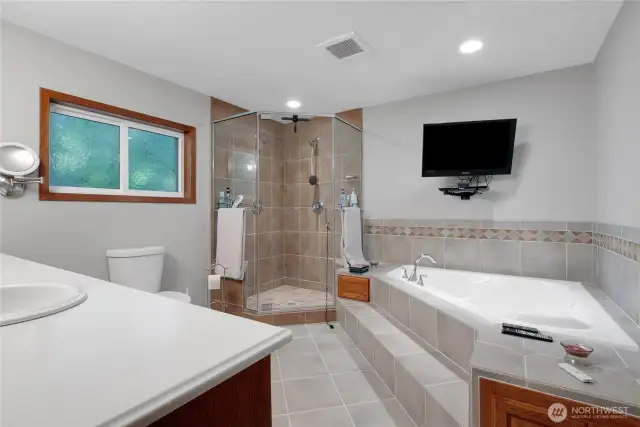 The en-suite features a separate shower and a soaking tub for relaxing baths, all set on elegant tile flooring.