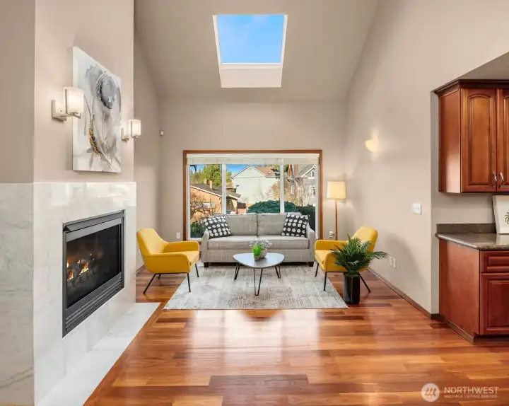 Family room offers beautiful hardwood floors, square gas fireplace with marble surround, French doors, 2-story vaulted ceiling, and skylight.