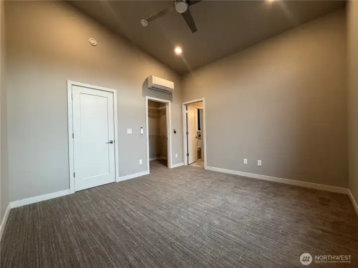 Primary with walk-in closet and vaulted ceilings and fan.