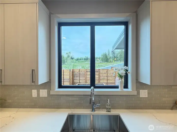 Lovely view out the kitchen window to the open space and PNW views.