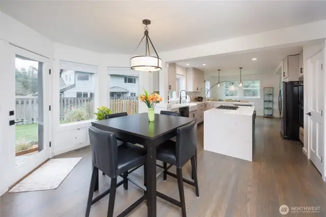Eating area between kitchen and family room has a door to the fully fenced backyard with patio.