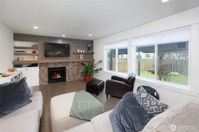 Family room has wall of windows and gas fireplace.
