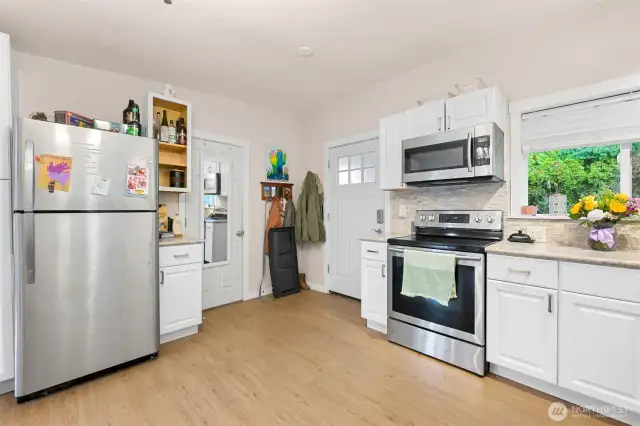Open kitchen with stainless appliances, vinyl plank floors