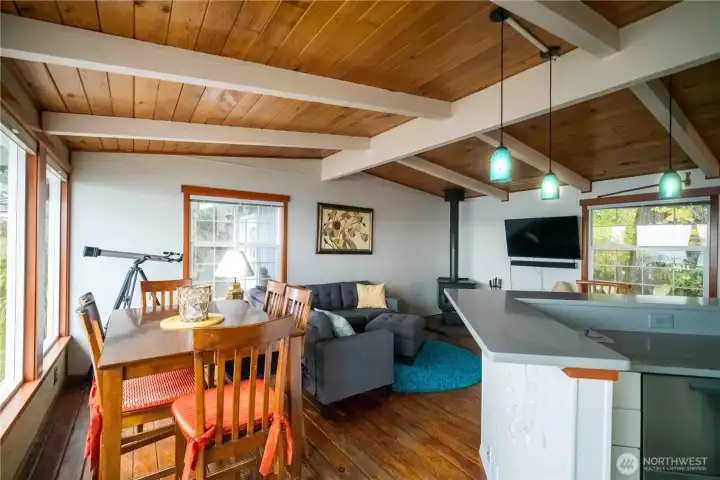 Open concept living area offers beautiful vaulted ceiling with exposed beams & tongue & groove wood floors with wood burning stove. The dining room has a wall of windows with incredible Southerly view. Kitchen has wrap around quartz eating.
