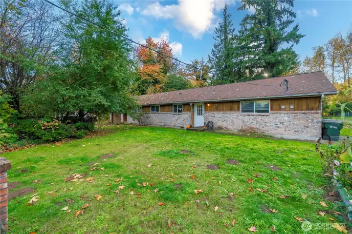 Front lawn and private entrance for Unit Two with wide windows for natural light. Established trees frame the property, offering shade and separation from neighboring homes.