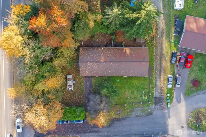 Aerial view showcasing the full duplex footprint, spacious lot, and mature tree canopy offering privacy. Driveways and off-street parking visible for both units, plus room for outdoor use or future improvements.
