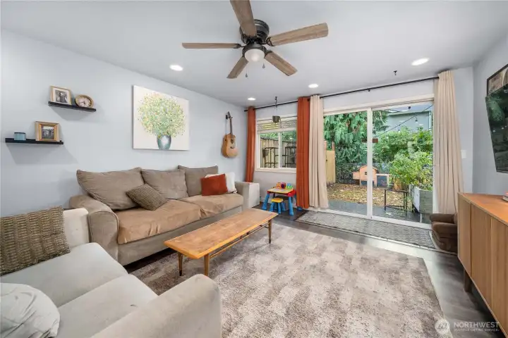 Unit 2 – Living Room: Natural light + backyard access  Large window and sliding glass door provide great natural light and direct access to the private backyard space.