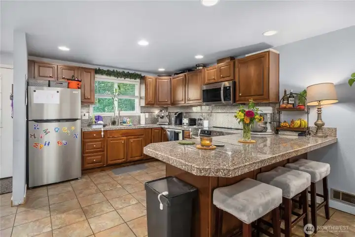 Unit 2 – Spacious Kitchen Layout  Bright and functional kitchen in Unit 2 featuring an open layout with an abundance of cabinet storage, durable tile flooring, and recessed lighting. Granite-style counters provide plenty of prep space for everyday cooking or entertaining.