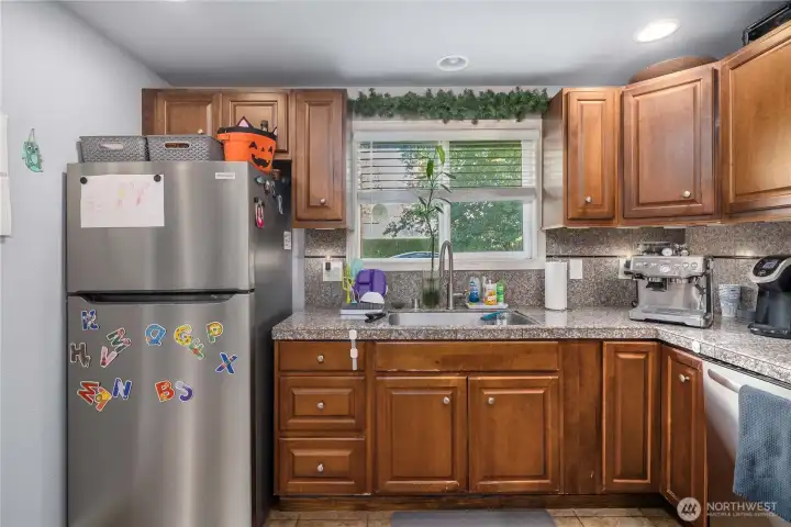 Unit 2 - Sink & Window View  Large kitchen window allows natural light to pour in while offering pleasant backyard views. Double-basin sink, updated fixtures, and generous counter space support everyday functionality.