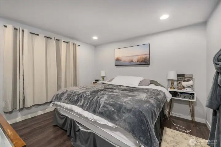 Unit 2 - Bright primary bedroom featuring updated flooring, recessed lighting, and a large closet for convenient storage. Neutral paint and natural light create a welcoming retreat within this versatile duplex home.