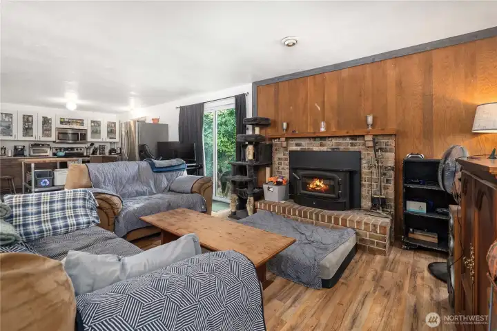 Unit 1 Brick-surround wood-burning stove provides efficient heating and a welcoming focal point, complemented by a slider that opens to the backyard for fresh air and additional natural light.