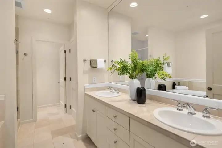 Primary suite dual vanity with limestone tile and linen closet