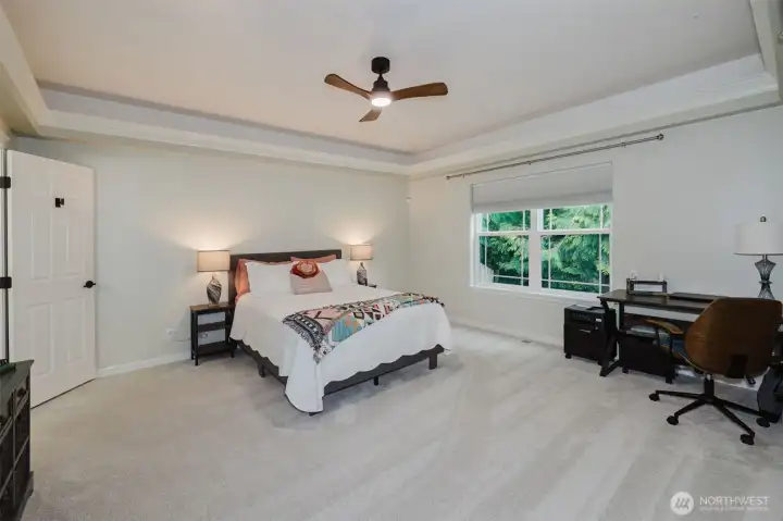 Grand Primary bedroom with tray ceiling and fan.