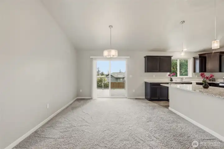 Dining off the kitchen with seating at the bar and a covered deck through the sliding glass door