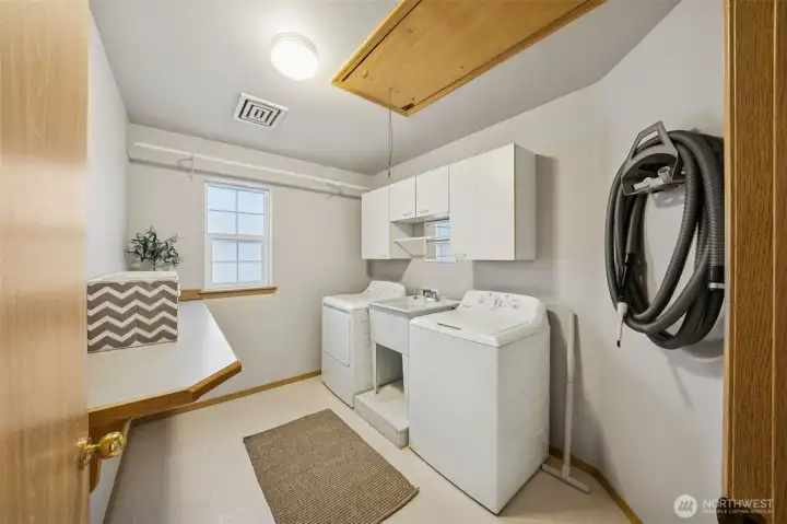 Upstairs laundry with utility sink, folding bar, cabinets and hanging rods