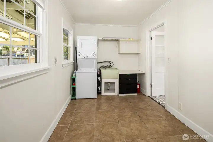 Flex room between kitchen and garage includes stacked  laundry machines which stay with the house and utility sink.