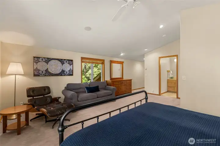 Spacious and serene primary suite retreat featuring vaulted ceilings, expansive windows, and peaceful forest views