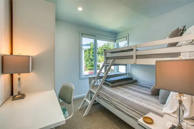 The third bedroom is furnished with a bunk bed and a home office area.