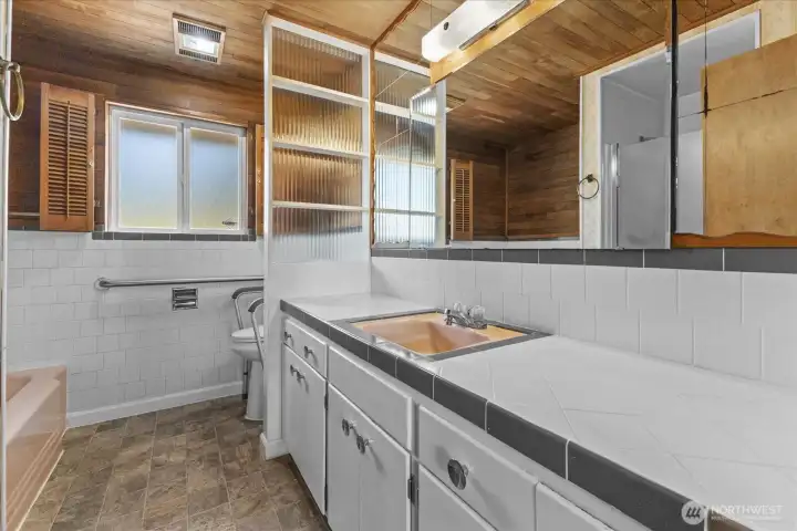 Main bathroom has unique wood anhancements and original pink sink and tub