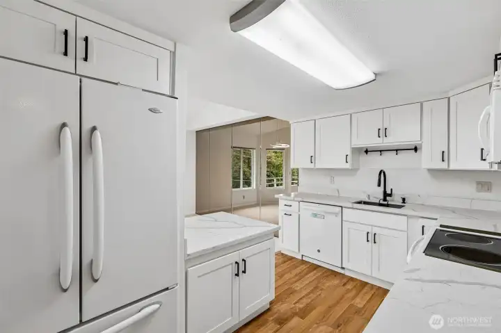 Kitchen with abundant cabinetry, modern black fixtures, and mirrored accent wall.