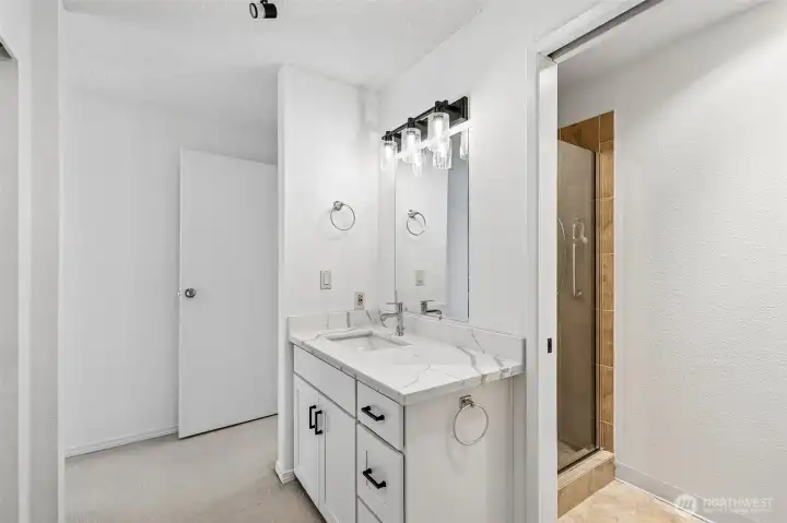 Updated vanity with quartz-style countertop and modern lighting.