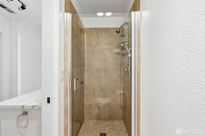 Tiled walk-in shower with glass enclosure.
