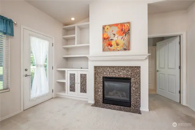 Gas fireplace has custom built-in shelving. Door on the right leads to the primary suite.