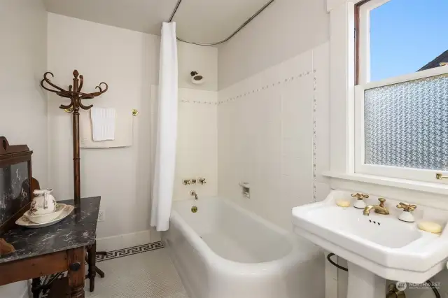 Full bathroom with original porcelain tiled flooring & cast-iron soaking tub.