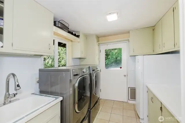 The utility room is tucked behind the kitchen and boasts a folding table, ample storage, utility sink, washer/dryer, windows that overlook the Hood Canal, and a doorway to your deck and forest view.