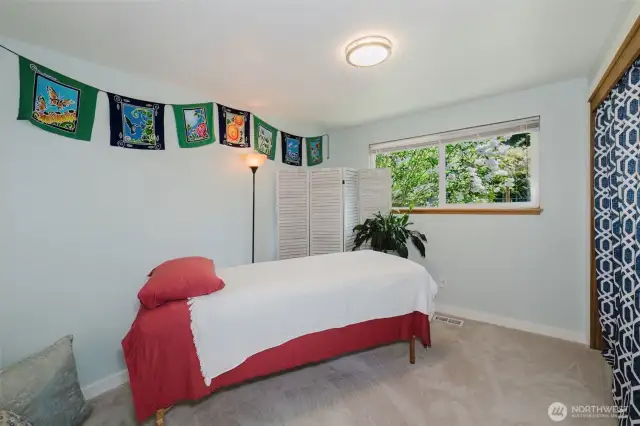 Looking into the second bedroom with windows looking out to the courtyard and lush garden.