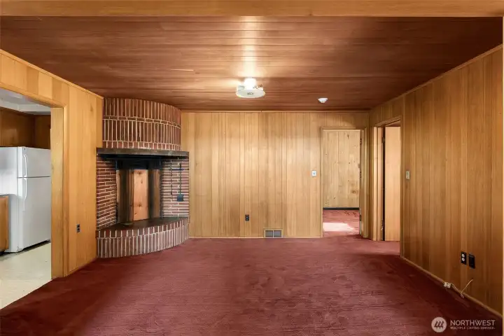 Warm and inviting living area featuring rich wood paneling and a classic brick, wood-burning fireplace