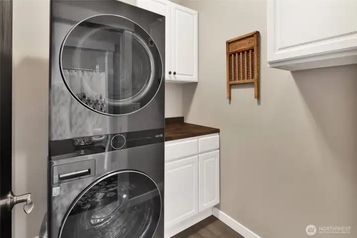 The laundry room includes the stacked washer and dryer plus a cabinet for storage and butcher block surface.