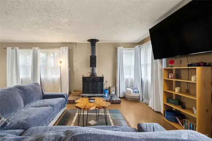 The living room feels warm and inviting, made cozy by a wood stove with a classic brick hearth.